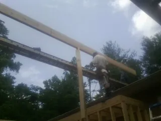Carpenter setting a ridge beam over a new addition frame — Ice Dam Removal by Roofing Brothers in Durant