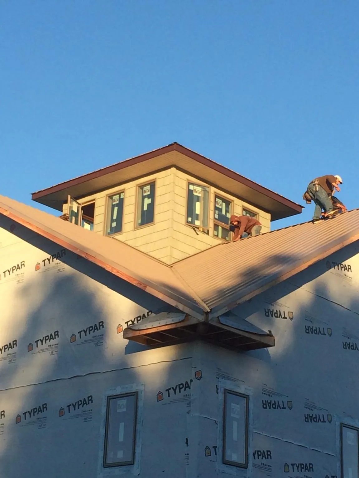 Roofers working around a rooftop cupola on a new metal roof at sunset — Roof Waterproofing in Durant by Roofing Brothers
